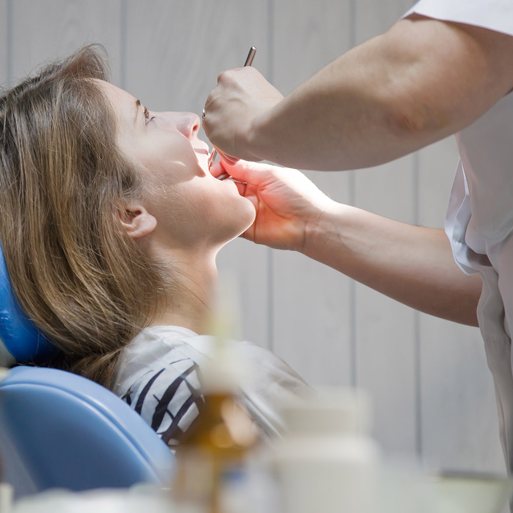 Dentist working inside the mouth of a female patient.