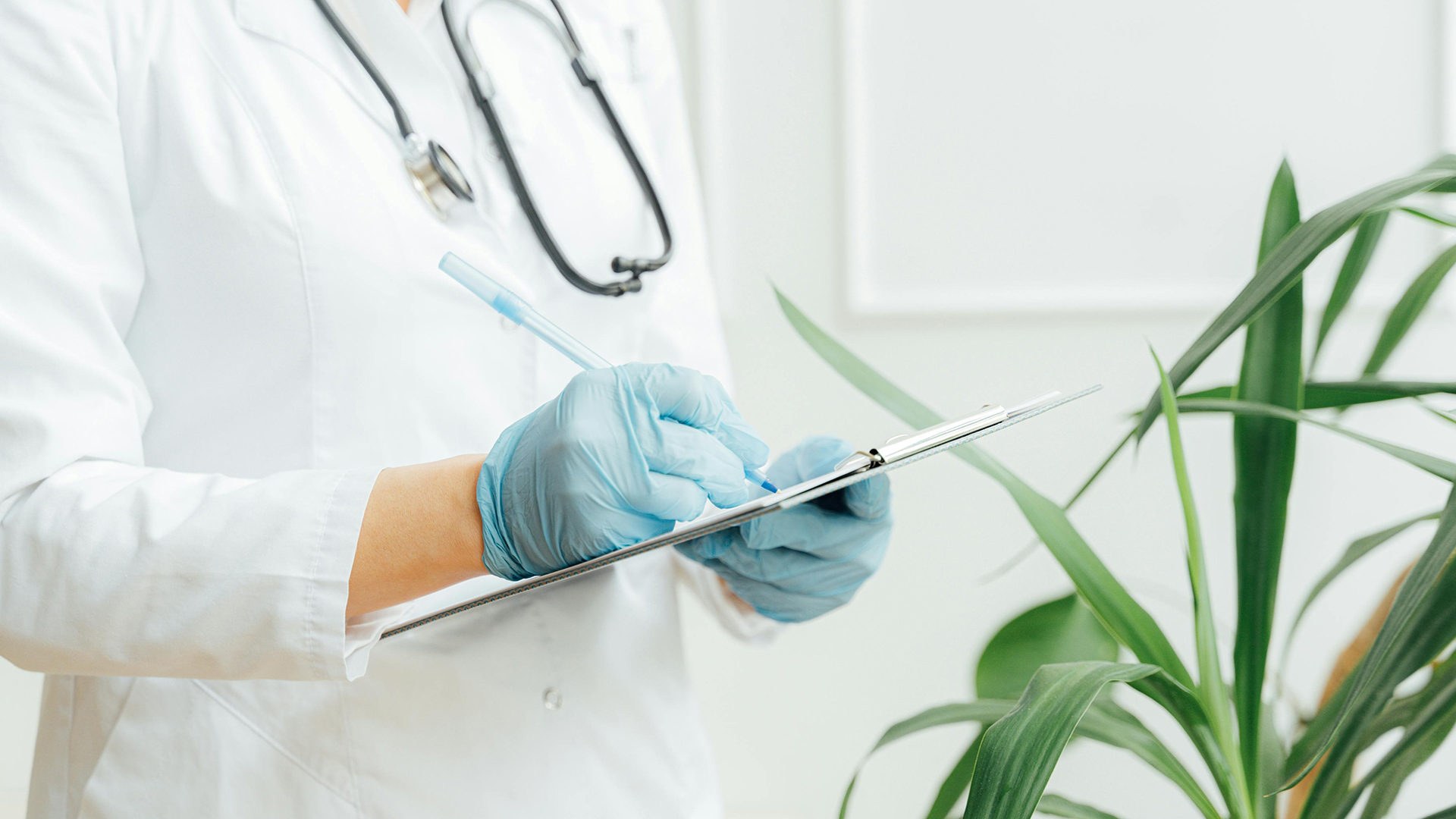 Doctor writing on a document attached to a clipboard.